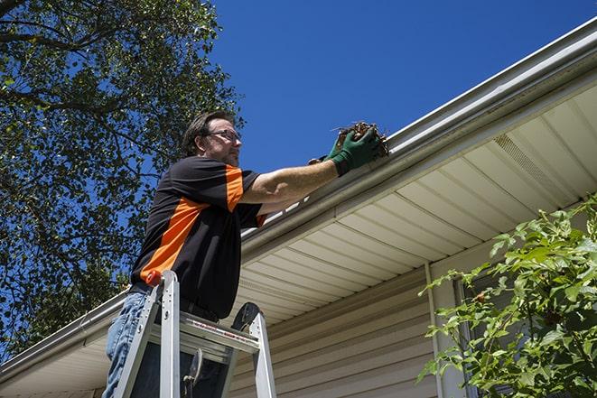 a person repairing a gutter on a residential roof in Colon